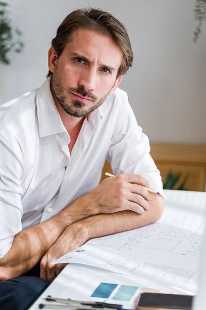 istock Man reviewing architecture plans at desk in office 2238012608