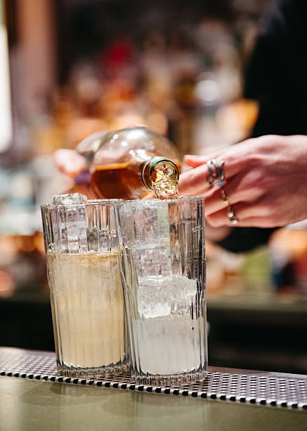 istock Bartender pouring liquor into iced glasses at a bar. 2238014127