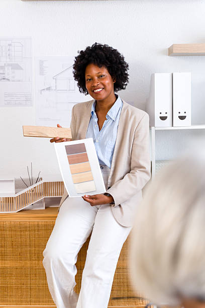 Woman architect smiling, presenting wood material options to a client