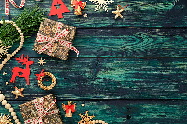 istock Cozy holiday flat lay with pinecone-patterned gifts, straw ornaments, red decorations, and pine branches on teal wood. Merry Christmas and Happy New Year concept. 2238015200