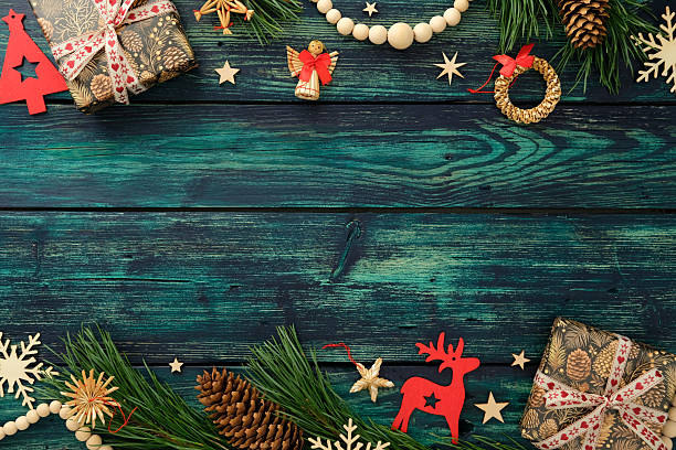 istock Rustic Christmas flat lay with pinecone gifts, straw ornaments, red cutouts, and pine branches on teal wood table. Top view. 2238015341