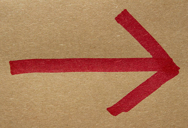 Red hand drawn arrow on brown kraft paper, closeup