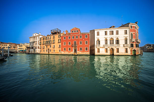 Boats drift peacefully as the afternoon sun reflects on the water near Palazzo Labia, where Canal Cannaregio meets the Grand Canal in Venice.
