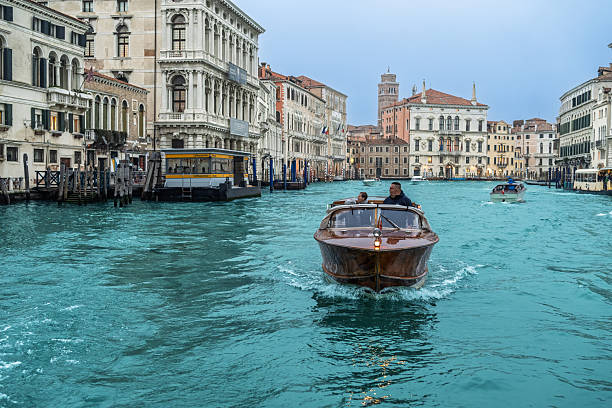 Visitors glide along the Grand Canal in Venice, surrounded by Ca' Rezzonico and Palazzo Balbi, showcasing stunning baroque and renaissance designs.
