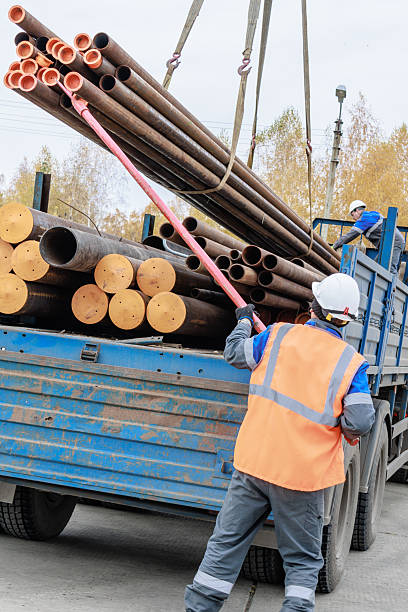 istock Construction Worker Loading Pipes onto Truck at Job Site 2238030908