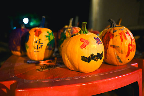 Hand-painted pumpkins displayed outdoors during a festive halloween autumn night