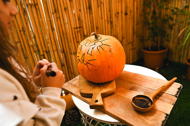 Child drawing spiders on a pumpkin for halloween decoration