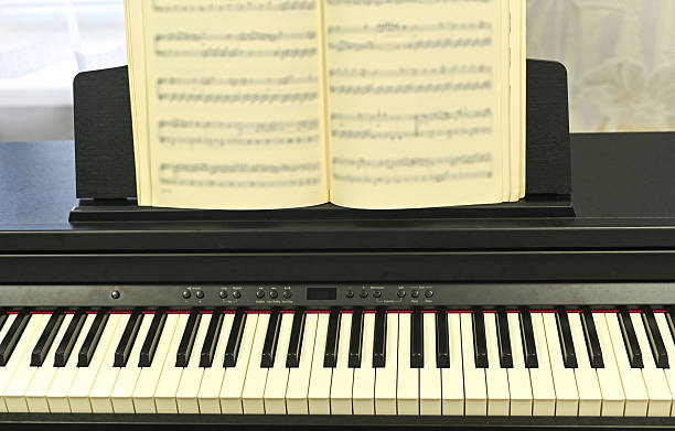 istock Notebook with musical scores placed on sleek electronic piano, 2238034930