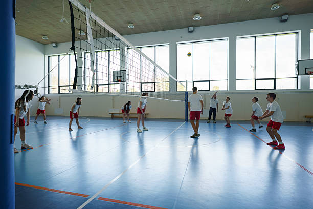 Students playing volleyball on court during physical education class.