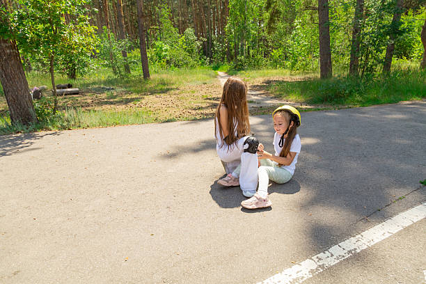 Asian little girl tying her sports shoes laces in the park for jogging with nature background. Kid tying shoes. Little girl struggling to tie shoe laces. Child learning fine motor skills.