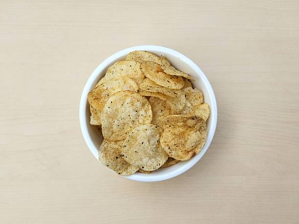 Seaweed flavored potato chips in white bowl on wooden table background. Flat lay