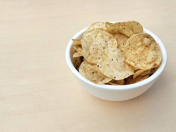 Seaweed flavored potato chips in white bowl on wooden table background. High angle view