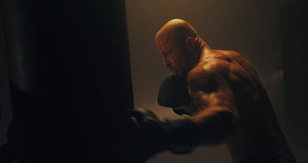 istock Sportsman training for a boxing match in a dark room. Practicing on a punching bag 2238041952