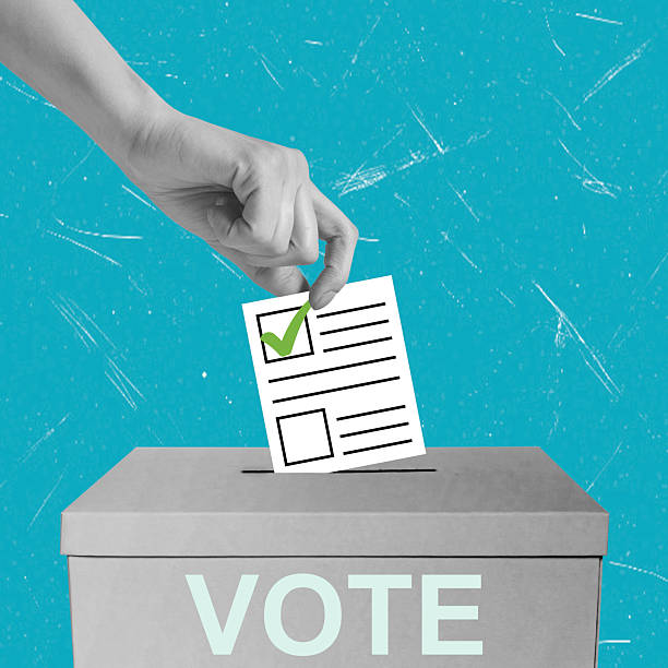 istock Art collage, Voting in progress with a hand placing a ballot into a box on a bright blue background 2238042028
