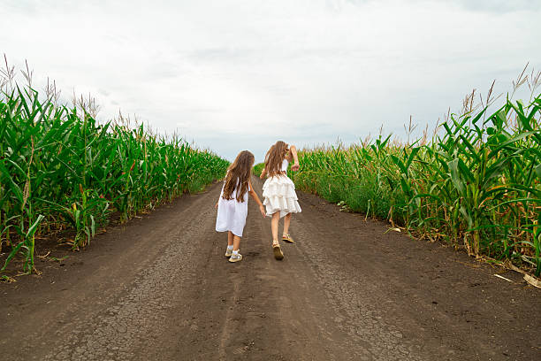 two girls running in a corn field in summer