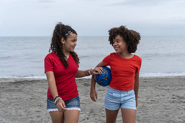 Teenagers playing catch on the beach in front of the Promenade des Anglais in Nice, Alpes-Maritimes, France.\nPartly cloudy spring day.\nShot with Canon R5