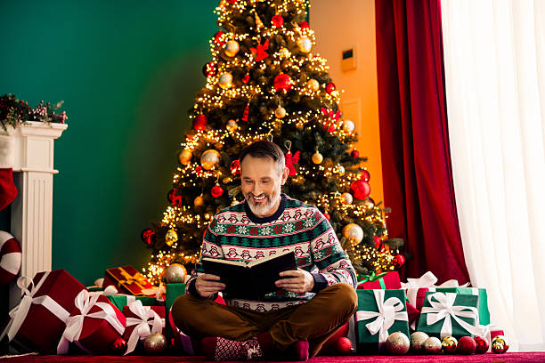 istock Festive elder reading by a Christmas tree with gift decorations in a cozy home during winter holidays 2238053417