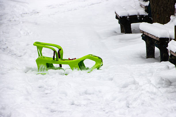 Girl falling while tobogganing on snowy hill during winter.