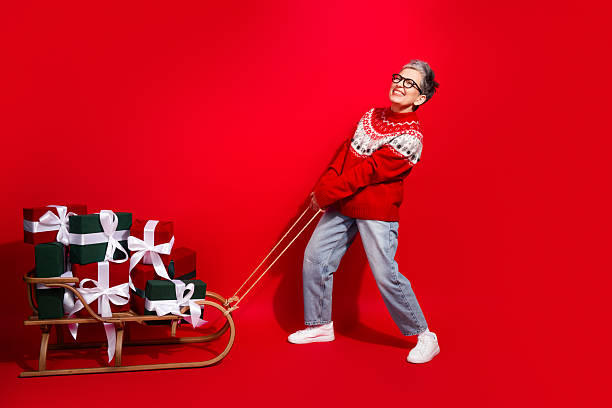 istock Festive woman pulling gift-laden sled against vibrant red background for Christmas celebration and holiday cheer promotion 2238055669