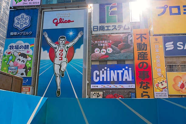 Osaka, Japan - December 12, 2024: Glico famous billboard with seamless lane from building against sunlight. Famous travel destination at Dontonbori district.