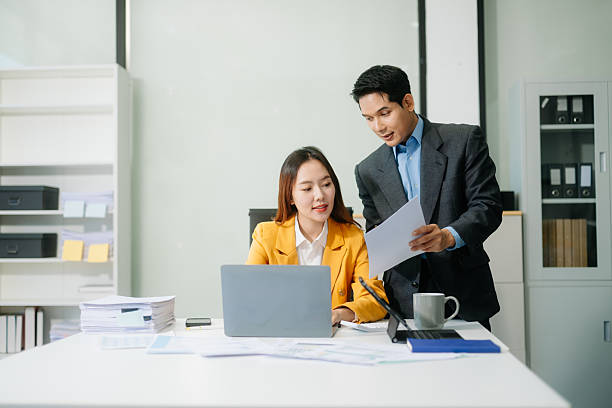 istock Two asian business workers talking on the smartphone and using laptop at office. 2238058071
