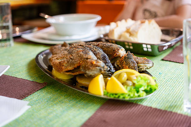 Restaurant specializing in traditional fried trout fish, serving a fresh platter with lemon wedges and green olives
