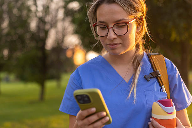 istock Young female nurse in blue uniform outdoors checking phone before going to work 2238061250