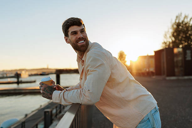 istock Handsome man drinking coffee and enjoying sunset at the harbor 2238062504