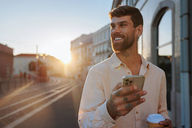 istock Handsome young manager using smartphone and drinking coffee at sunset in the city 2238062510