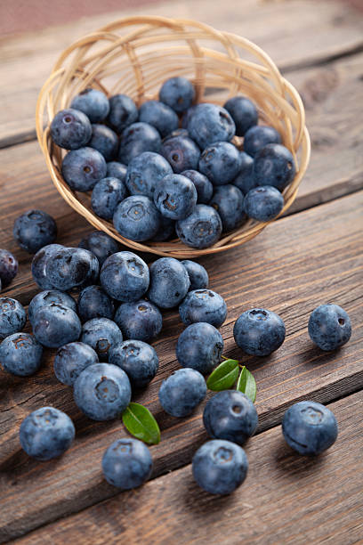 istock Blueberries with mint leaves scattered from basket on wooden rustic table 2238066399