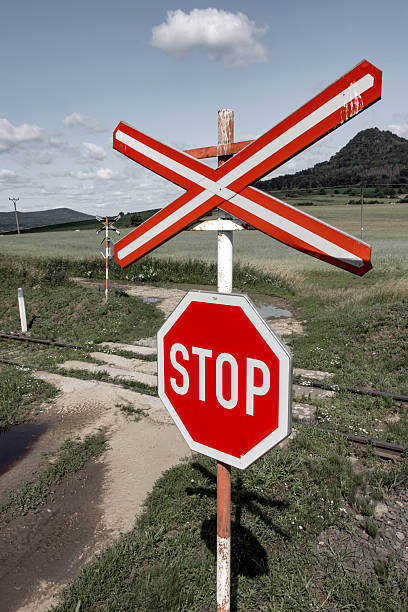 A red STOP sign before crossing the tracks.