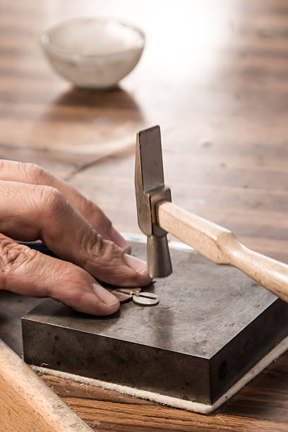 istock jeweler working with a hammer and silver earrings 2238070769