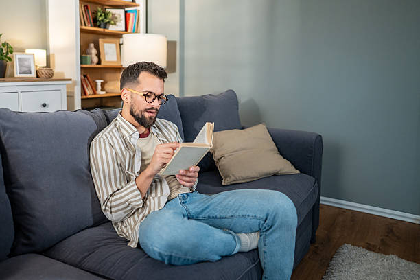istock Man relaxing on sofa, enjoying reading a book at home 2238070841