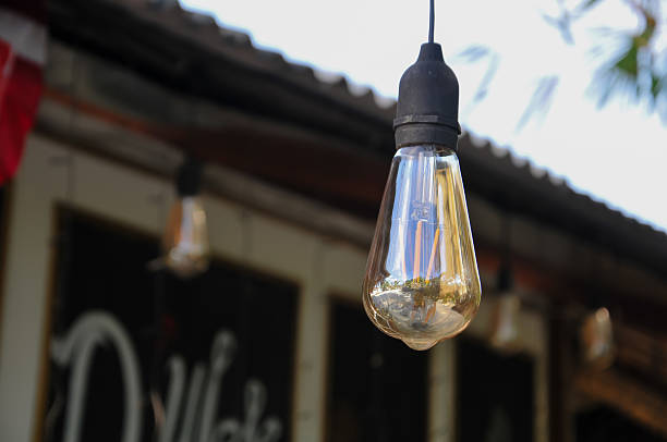 istock A single vintage incandescent light bulb hangs outdoors from a dark cable, featuring a reflective glass surface 2238078595