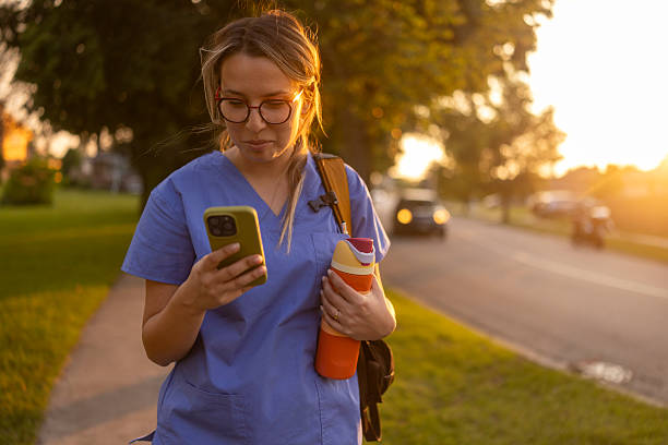 istock Focused female nurse in blue uniform outdoors checking phone before work at sunset 2238087643