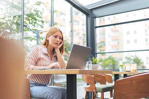 istock Young Woman Using Laptop While Sitting in Coffee Shop 2238089393