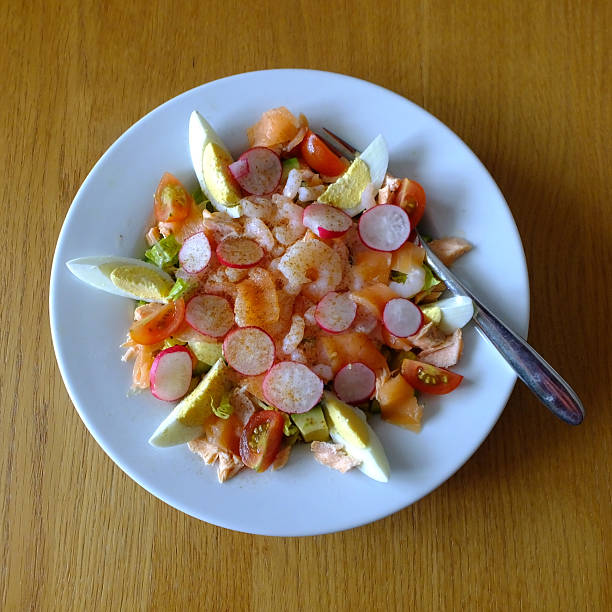 A cesar salad bowl filled with lettuce, tomatoes, egg and chicken. The salad is served in a clear glass bowl