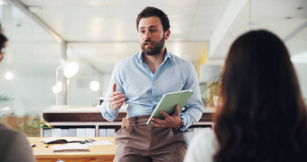 istock Meeting, business and man with tablet in office for planning, intern training and article feedback. People, digital and talking to team for schedule, coaching tips and headline ideas for publication 2238092350