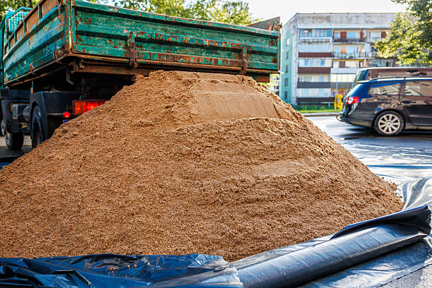 istock Green Truck Unloading Sand on Black Tarp in Urban Setting 2238105935