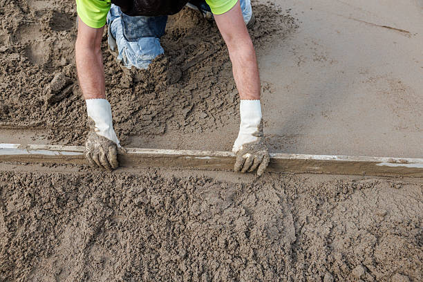 istock Worker Levels Wet Concrete with Straightedge Tool on Construction Site 2238106316