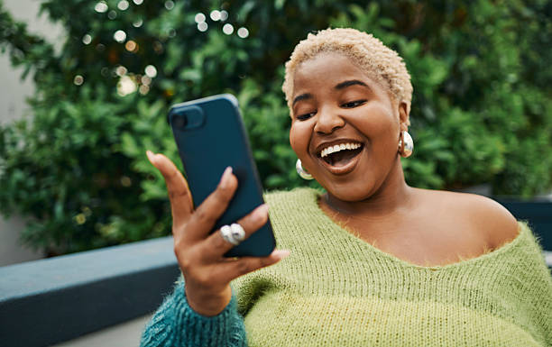 istock Joyful Woman Smiling Outdoors Holding Smartphone in Hands 2238106976