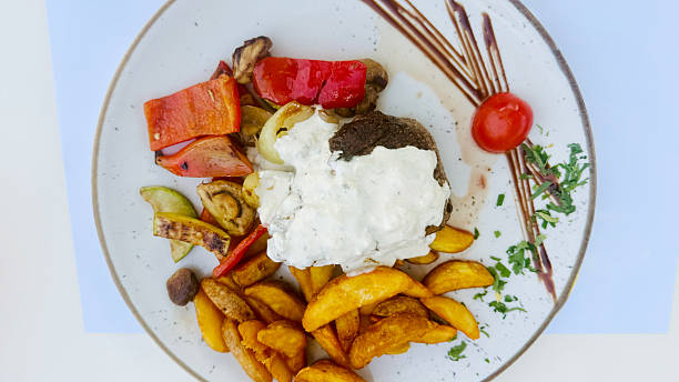 Plate of Steak with Vegetables and French Fries Garnished with Sauce