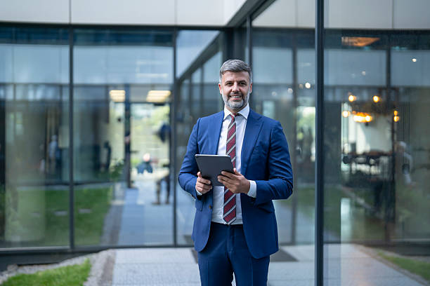 istock Smiling businessman holding digital tablet outside modern office building 2238108208