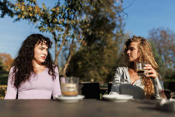 istock Two women engage in a lively conversation while seated outdoors, soaking in the sunshine on a clear day in a vibrant park 2238108723