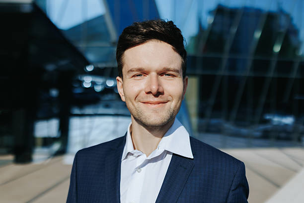 istock Smiling confident businessman in suit standing outdoors near modern office 2238111450