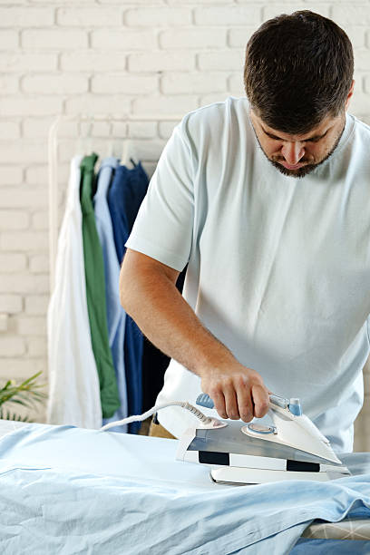 istock Man ironing a blue shirt in a well-lit laundry room during daytime 2238111751