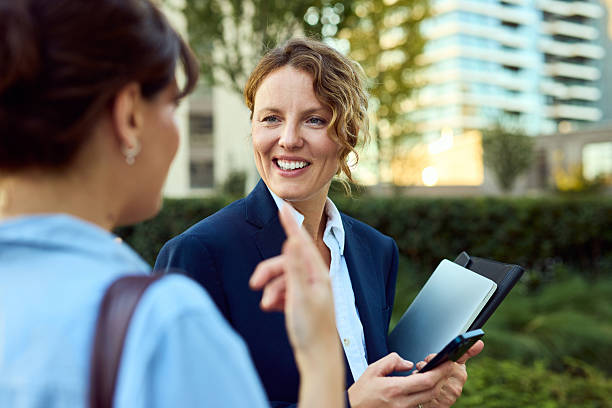istock Business Women Networking Outdoors: Confident Conversation With Tablet In Urban Setting 2238112399