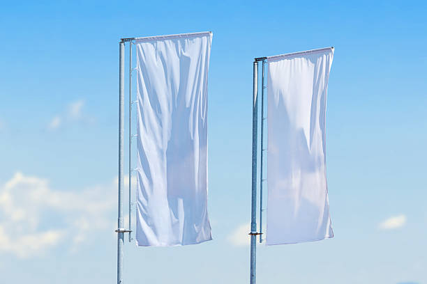istock Two tall vertical white flags waving on metal poles against clear blue sky, minimalistic outdoor advertising concept 2238112443