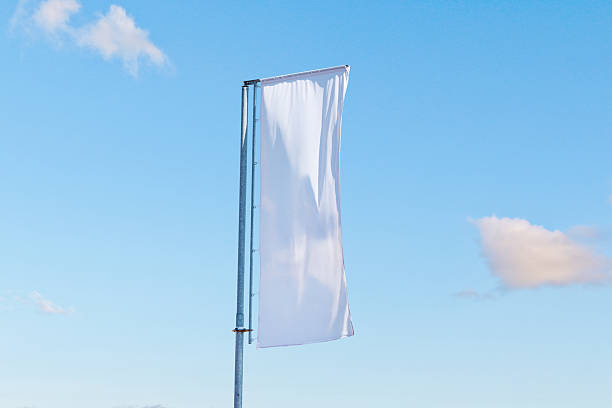 istock Vertical white advertising flag on metal pole fluttering in wind under clear blue sky, minimal promotional template 2238112454
