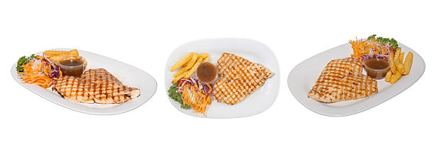Grilled chicken breast meal: A culinary composition, showcasing perfectly grilled chicken breast alongside golden-brown fries and a vibrant mixed salad with a rich sauce.